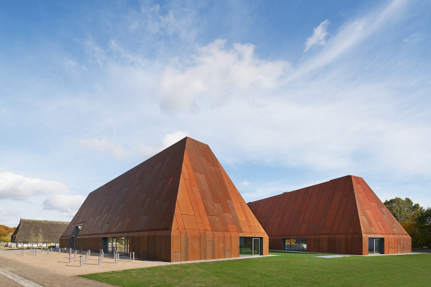 Die Neubauten für das Landesmuseum für Volkskunde im Museumsdorf Molfsee erinnern hinsichtlich ihrer Formgebung an regionale Bauernhäuser. Mit wetterfestem Baustahl einheitlich bekleidet werden Dach und Wand durch architektonische Transformation zur skulpturalen Großform, die Gebäude selbst zu Artefakten. © Architektur: ppp architekten + stadtplaner gmbh | Foto: Stephan Baumann