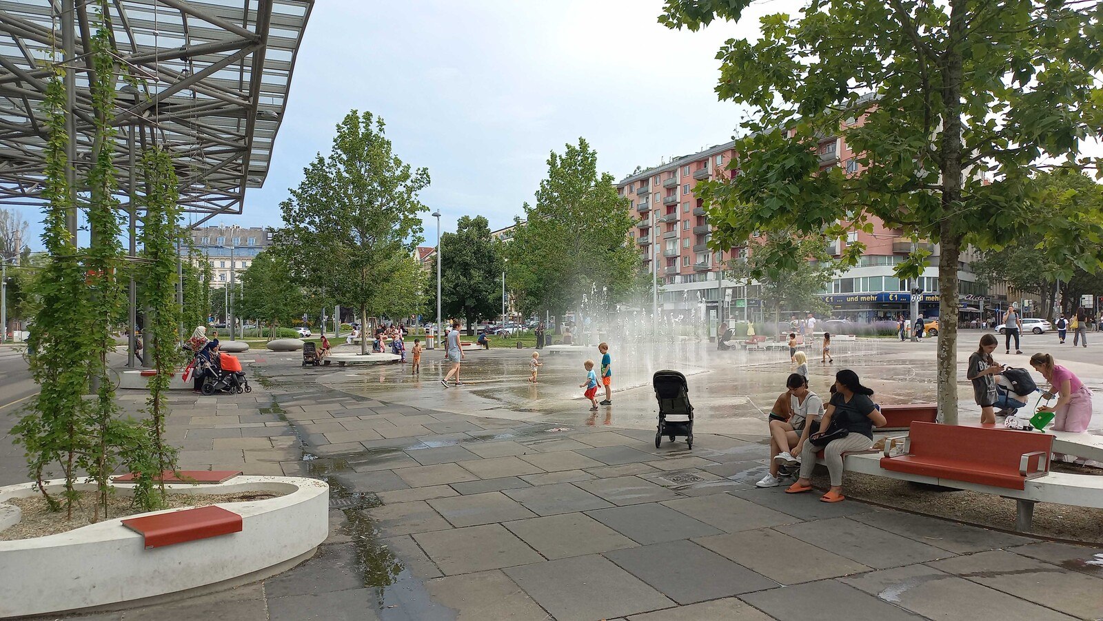 Cooler begrünter Praterstern: Auf einer der heißesten Betonwüsten Wiens wurde mit Unterstützung der MA 22 ein Coolspot mit großkronigen Schwammstadtbäumen, Wasserspiel und Vertikalbegrünungen geschaffen. An heißen Sommertagen haben dort Kinder ähnlich viel Spaß wie in einem Freibad. © Jürgen Preiss