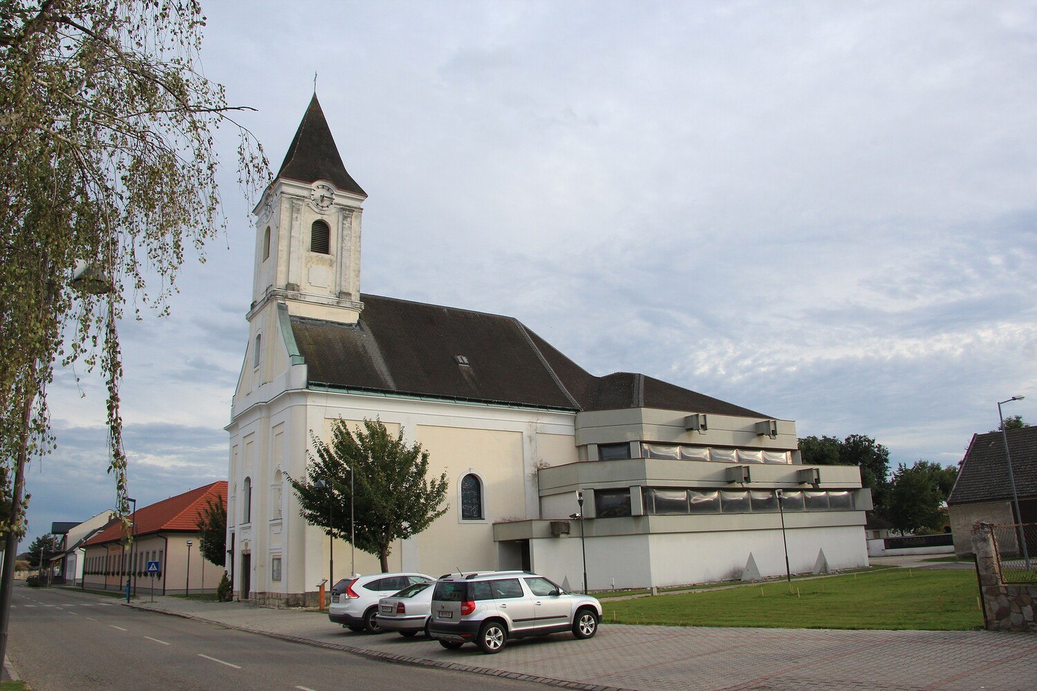 Gesamtansicht der katholischen Pfarrkirche hl. Margaretha in der burgenländischen Gemeinde Apetlon mit dem Zubau und den gewölbten Plexiglasfenstern im Originalzustand. © WikiCommons/Karl Gruber