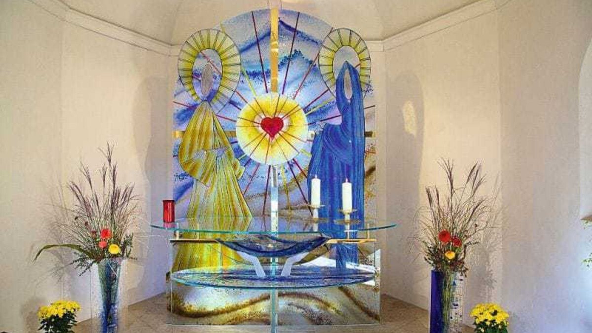 Der beeindruckende Altar der Kapelle in Absam: ganz aus Glas mit ineinander verschmolzenen Farbgläsern, lebensgroßen Figuren und rotem Glasherz im Zentrum.