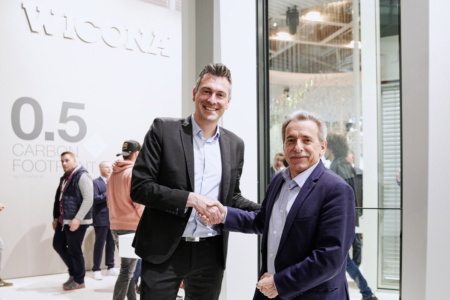 Besiegeln ihre Partnerschaft für nachhaltige Fassaden: Bruno Mauvernay (l.), Direktor des Geschäftsbereichs Glasfassaden bei Saint-Gobain und Henri Gomez (r.), Vice President bei Hydro Building Systems. © Mediashots