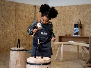 Mädchen bearbeitet in der Holzwerkstatt seinen persönlichen Holzkreisel