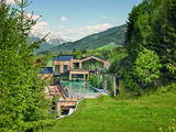 Naturhotel Forsthofgut Leogang Aussenansicht mit Wiese und Pool