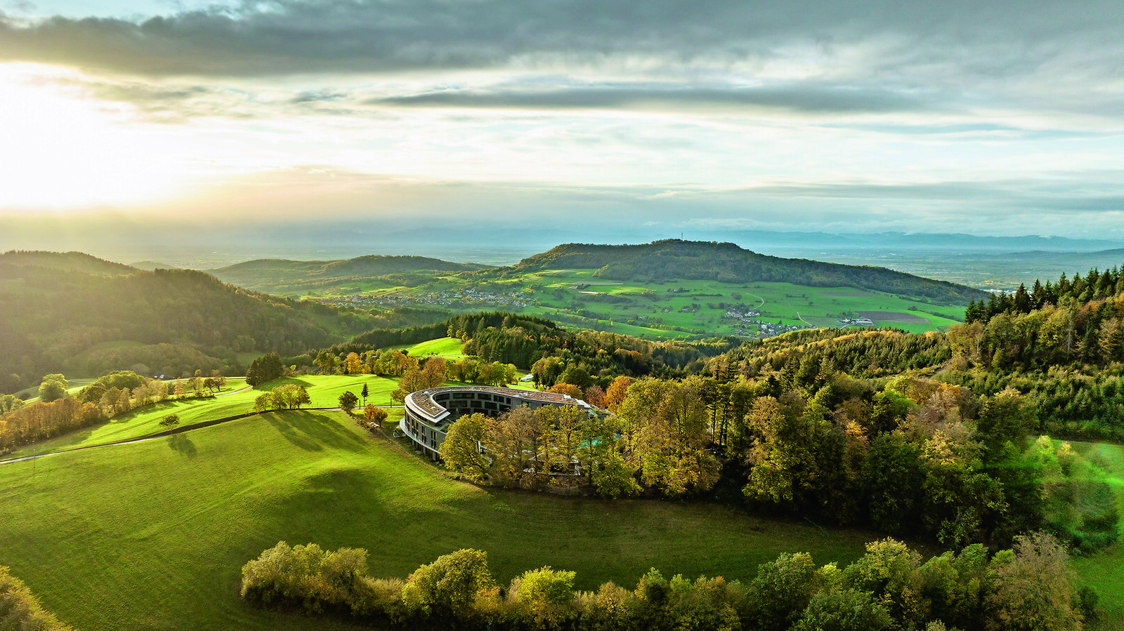 Die ellipsenförmige Architektur des Gesundheitsresort Luisenhöhe fügt sich in die sanfte Hügellandschaft des Schwarzwalds ein. © hansgrohe