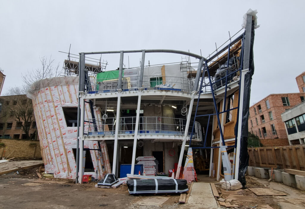 Die geneigten Holzrahmen-bau-Außenwände rechts im Bild (Wand A) und ganz links im Bild (Wand C) sind montiert. Die Stahlkonstruktion für den mittle-ren Teil (Wand D) ist vorbereitet. Foto: Züblin Timber