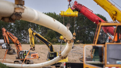 Eine Gaspipeline inmitten einer Baustelle. Rundherum stehen viele Bagger und ein Kran.